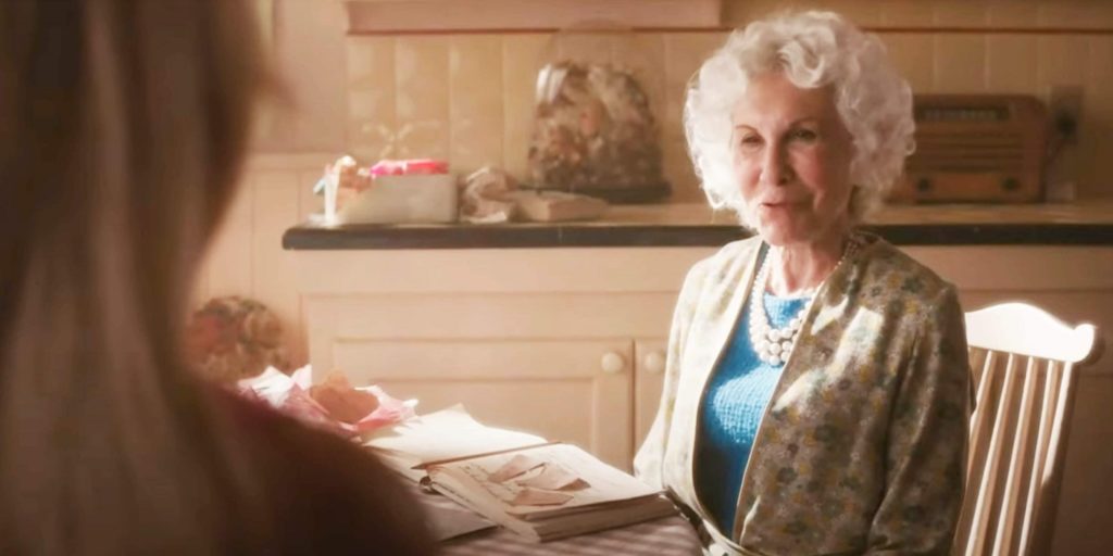 Ruth Handler portrayed by Rhea Perlman sits at kitchen table talking to Barbie.